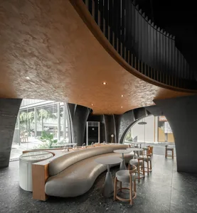Modern, minimalist café with a concrete interior and curved seating area.