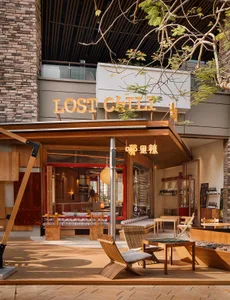 Outdoor patio of a modern restaurant with wooden furniture and structural elements.