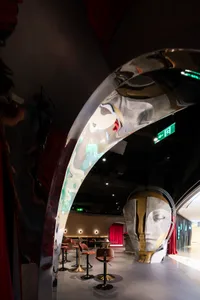 Modern interior of a shopping center featuring a polished metal archway and red curtains.