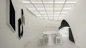 White minimalist interior design of a restaurant/cafe with a round white table, white stools, and framed black artwork on whi
