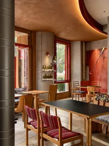 A modern café interior featuring a wooden counter with red accents and mixed materials.