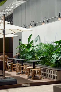 Modern minimalist cafe exterior with concrete, rattan, and glass materials.