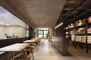 Interior design of a modern restaurant bar with concrete walls and wooden tables and chairs.