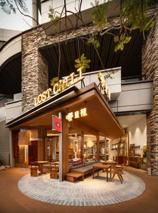Outdoor seating area at a modern restaurant with wooden furniture and a stylish sign.