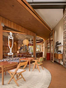Modern restaurant interior with wooden tables, glass walls, and stone walls.