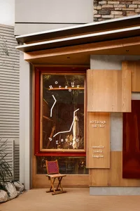 Modern retail storefront with a wood window display featuring a neon sign, seating, and a clean, contemporary design.