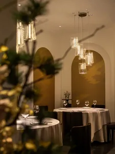 A modern restaurant interior with glass lighting fixtures hanging from the ceiling, and tables set for dining.