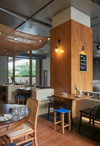 Wooden tables, concrete wall, and fabric canopy in a restaurant interior