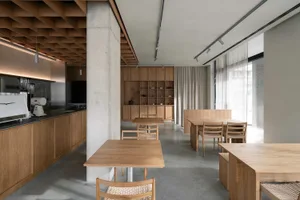 A minimalistic cafeteria with wooden furniture and concrete flooring.