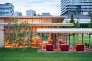 Modern restaurant exterior featuring wooden tables and a white-tiled facade.