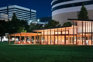 A modern cafe exterior with wooden bar and seating area during the night.