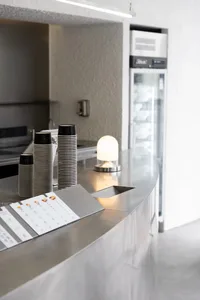 Stacked disposable coffee cups on a sleek metallic coffee counter.