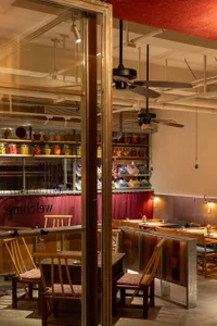 Industrial-themed restaurant interior with wooden furniture and shelves displaying jars and baskets.