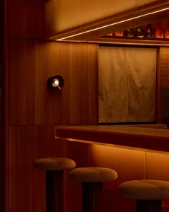 Modern bar area with a wooden counter and stools