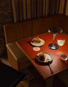 Serving of a sandwich and a cocktail on a wooden table in a restaurant setting.