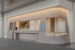 A modern coffee shop interior featuring a minimalist design with concrete elements.