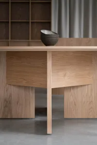 Modern dining room featuring an oak wood table and stacked black bowls.