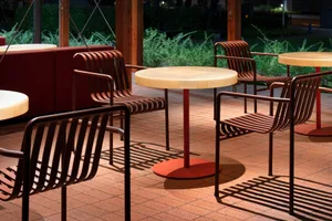 Outdoor café seating area with metallic furniture and red table tops.