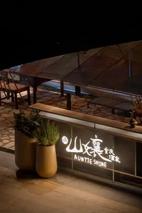 Modern restaurant exterior with metal and concrete surfaces and potted plants.