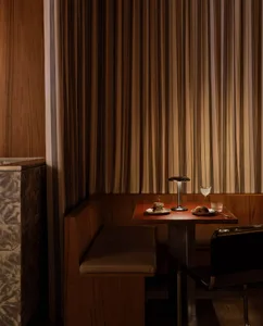 A modern restaurant interior featuring a wooden table with food and drinks.