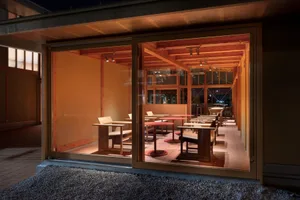 A modern restaurant interior featuring wooden tables and chairs, warm lighting, and a warm, inviting atmosphere.
