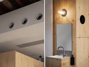 Modern minimalist bathroom with wood and metal elements, featuring a sink, mirror, and lighting fixtures.