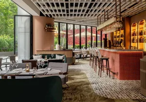 現代餐廳酒吧室內，搭配木質家具、玻璃層架、金屬吧凳與布料點綴。