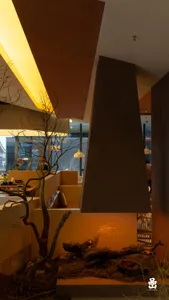 Industrial-style restaurant interior with wooden elements, cozy lighting, and a central fireplace.