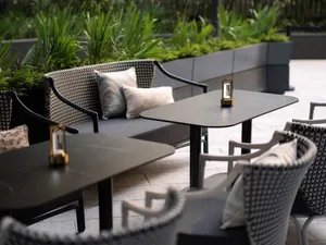 Outdoor seating area with metal and wicker furniture in a modern cafe setting.