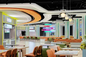 A spacious cafeteria with modern interior design featuring colorful lighting and seating arrangements.