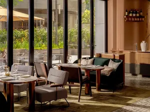 Modern dining room with clear glass walls, wood furniture, and upholstered seating.
