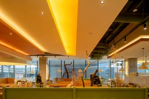 Modern restaurant interior with concrete walls, glass windows, and wooden accents.