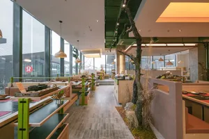 Modern restaurant interior with industrial design elements, featuring wooden furniture and concrete columns.