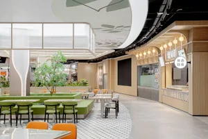 Modern restaurant interior featuring green upholstery on seating, wooden benches, and glass partition.