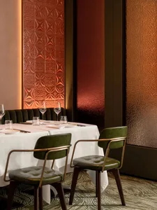 A meticulously designed restaurant interior with a minimalist aesthetic, featuring textured wallcoverings and a warm, invitin