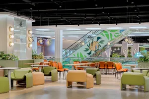 Modern restaurant with orange leather chairs and glass tables.