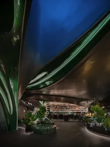 Modern restaurant bar with metal-cladding walls, green lighting, and green plants