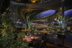 An interior design of a modern restaurant featuring metallic glass walls and a contemporary design aesthetic.