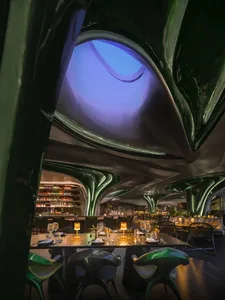Modern restaurant interior with metallic accents and a skylight.