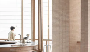 A modern cafe interior featuring wooden tables, brick walls, and glass windows.