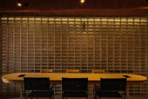 A modern conference room with glass block walls and a long, wooden dining table.