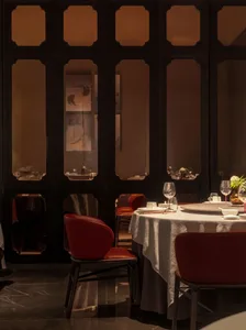 Modern restaurant interior with red leather chairs and round dining table.
