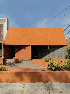An orange storefront with a concrete facade and a triangular roof, set against a clear blue sky.