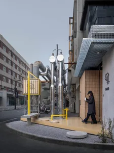 Urban industrial storefront with metallic pipes, glass panels, and wooden accents.