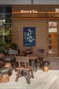 Industrial-style restaurant exterior with wooden tables, chairs, and stools.