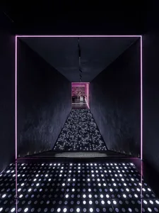 A minimalist interior space featuring a metallic, luminous staircase with a futuristic design.