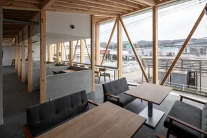 Interior of a modern coffee shop with wooden tables and concrete elements.