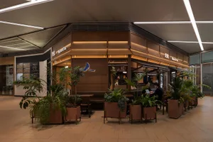 A modern coffee shop with wooden interiors, featuring plants and contemporary seating.