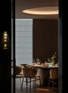 A modern dining room with dark wood and glass elements, featuring a round table set for eight people.