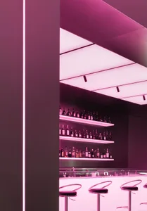 A modern, minimalist bar interior with a pink illuminated ceiling and shelves filled with bottles.